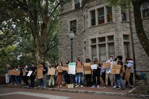 Student protestors stand in front of Castle with cardboard signs.