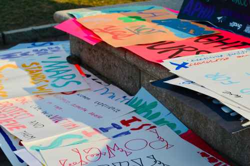 A collection of colorful signs on concrete steps protesting sexual violence.